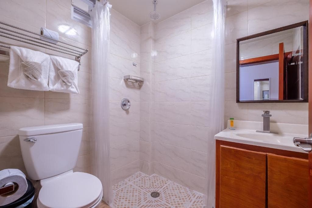 Modern bathroom featuring a shower, toilet, and sink with wooden cabinetry.