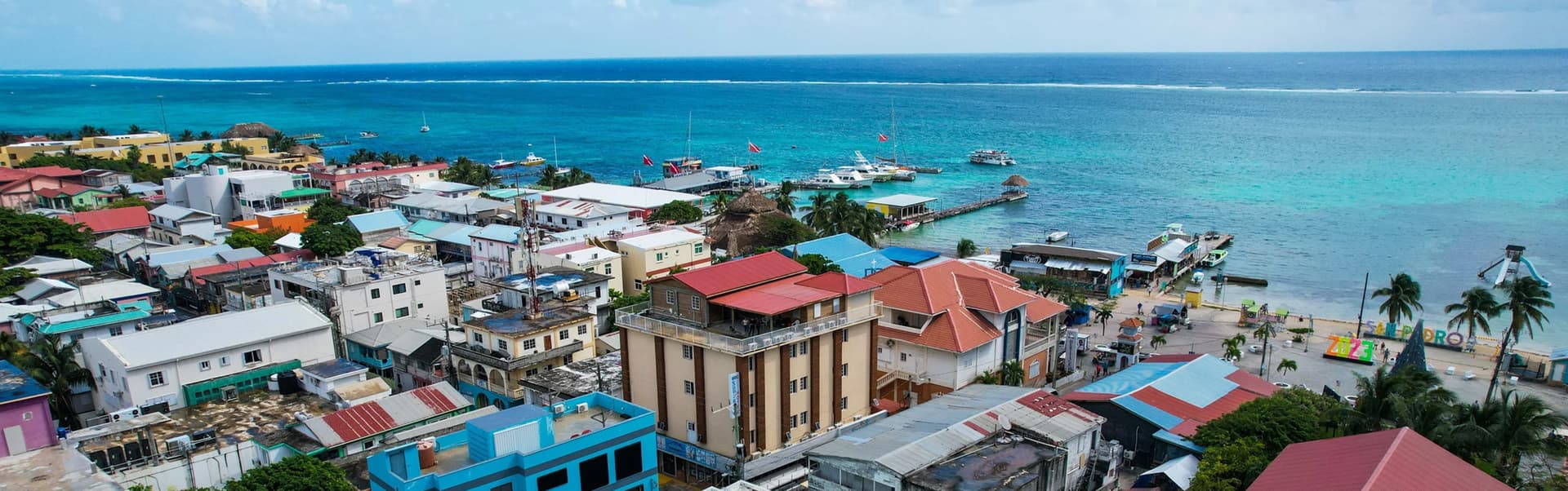 Aerial view of a colorful coastal town with vibrant buildings overlooking a turquoise sea.