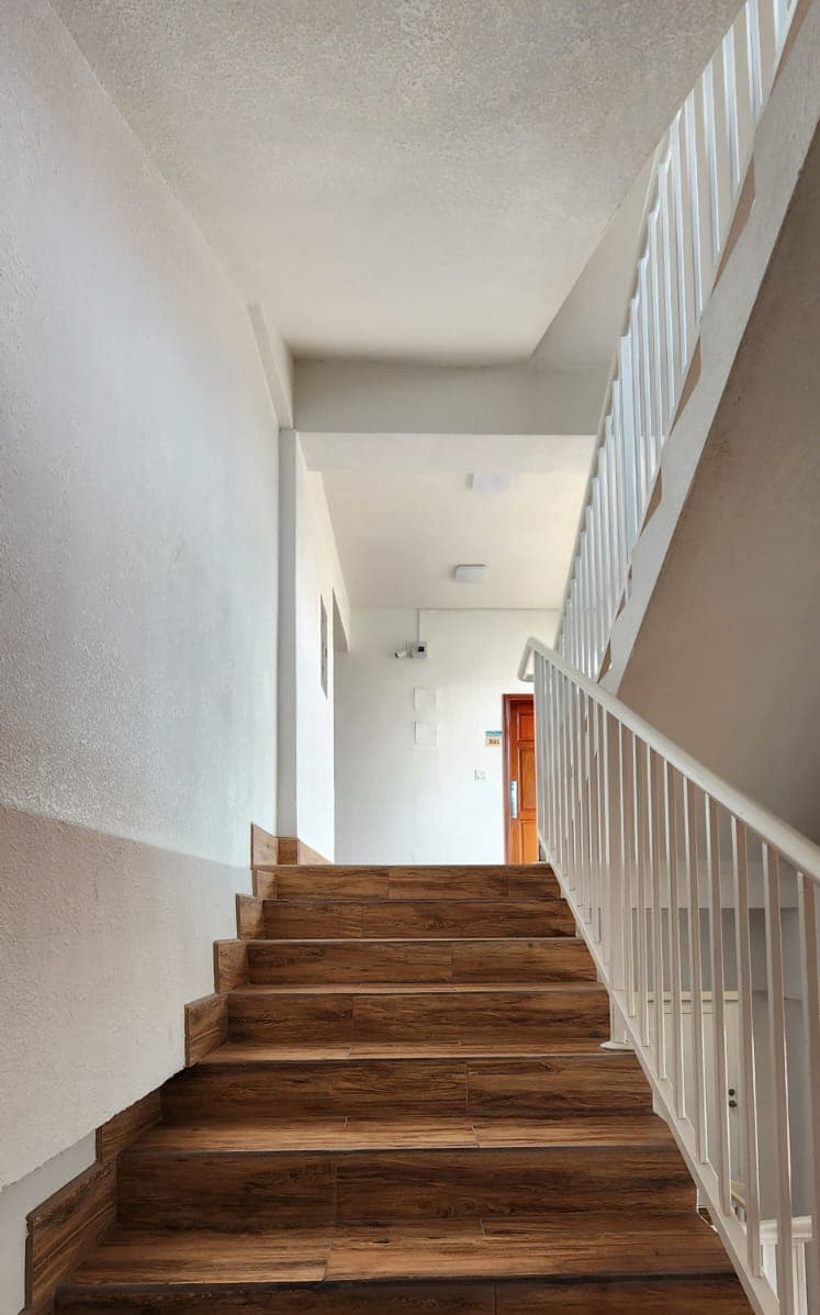 A staircase leading to a brightly lit hallway with a wooden door.