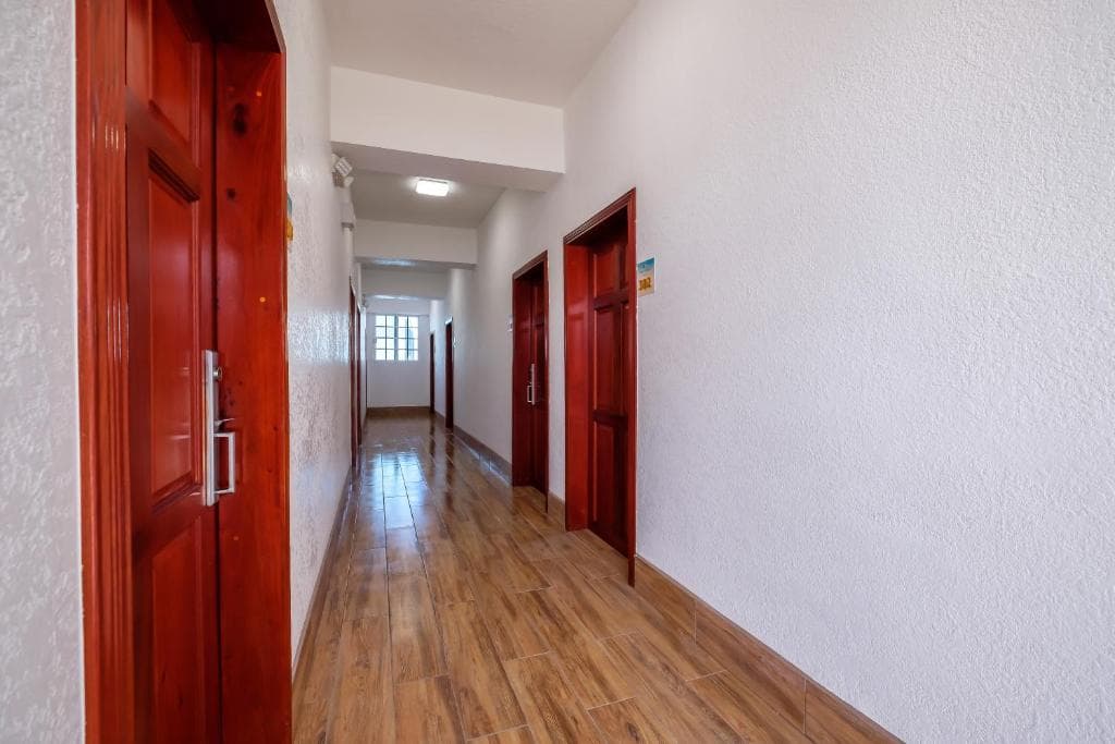 Long hallway with wooden flooring and red doors on either side.