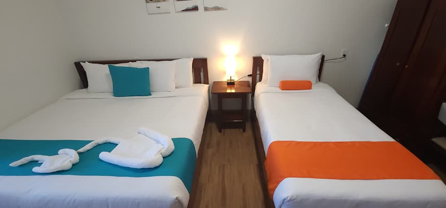 A cozy hotel room featuring two beds with colorful linens and a bedside lamp.