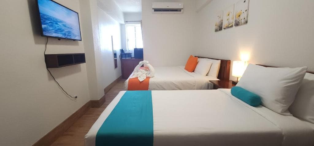 A modern hotel room featuring two beds, a wall-mounted TV, and bright decor.