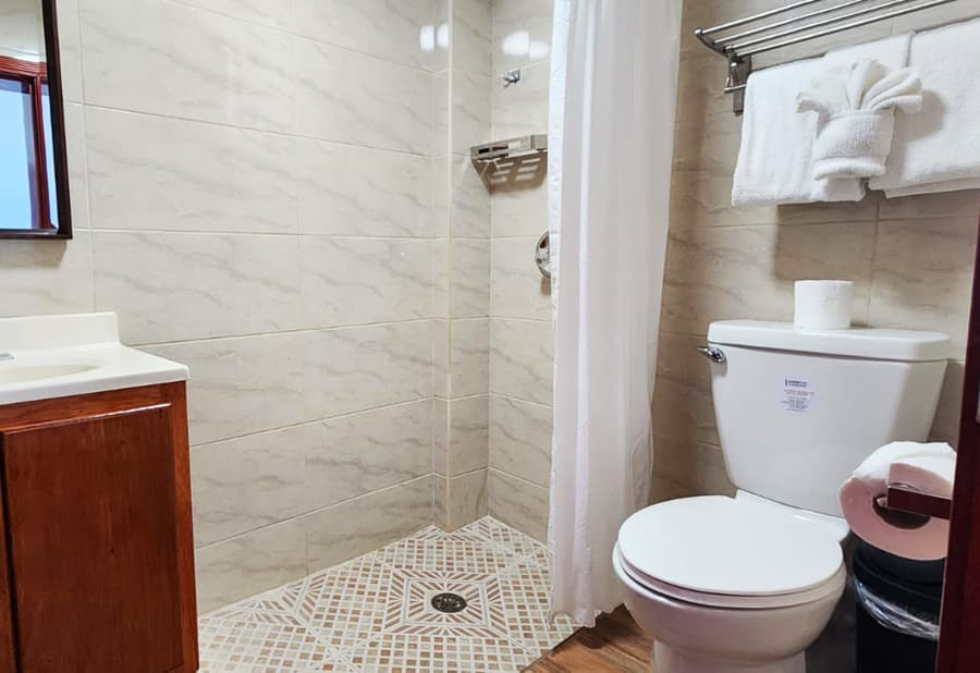 A tidy bathroom featuring a shower, sink, and toilet with light tile accents.