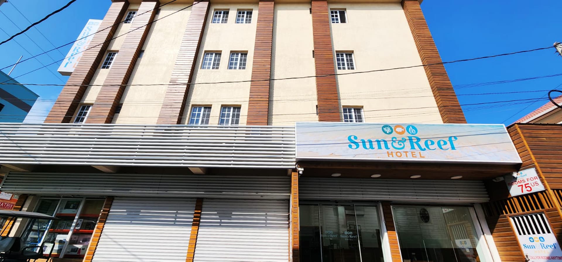 Exterior view of the Sun & Reef Hotel featuring a modern design and clear blue sky.