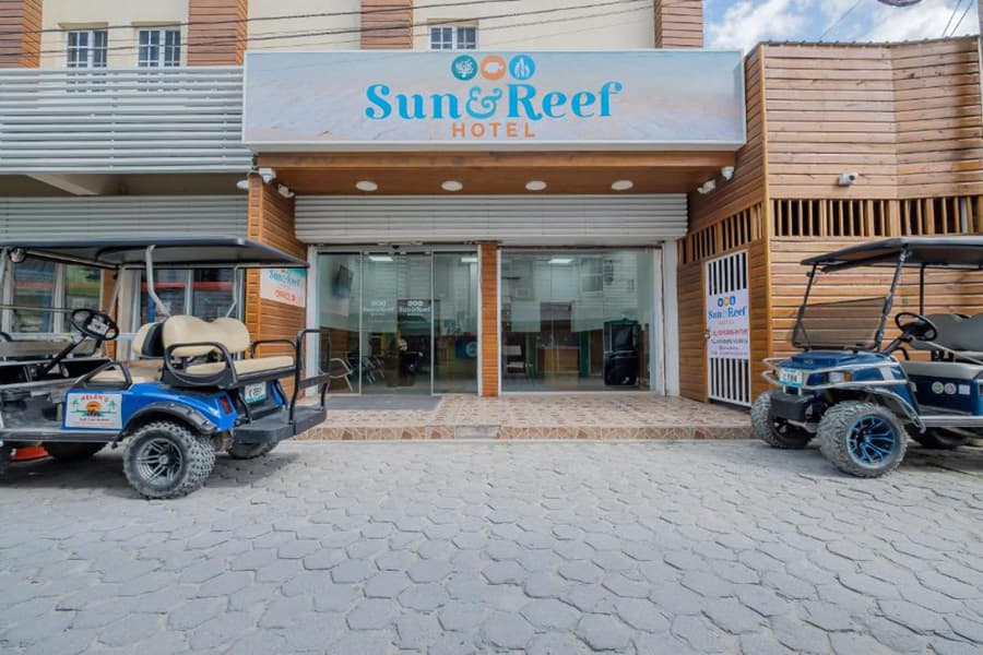 Exterior view of the Sun & Reef Hotel with two golf carts parked outside.