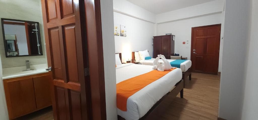A cozy hotel room featuring two beds, wooden decor, and a modern bathroom area.