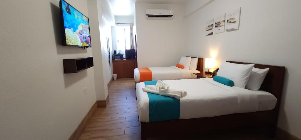 A cozy hotel room featuring two beds, a television, and minimalistic decor.