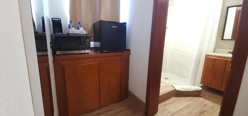 A view of a kitchenette area with a microwave and mini-fridge leading to a bathroom.